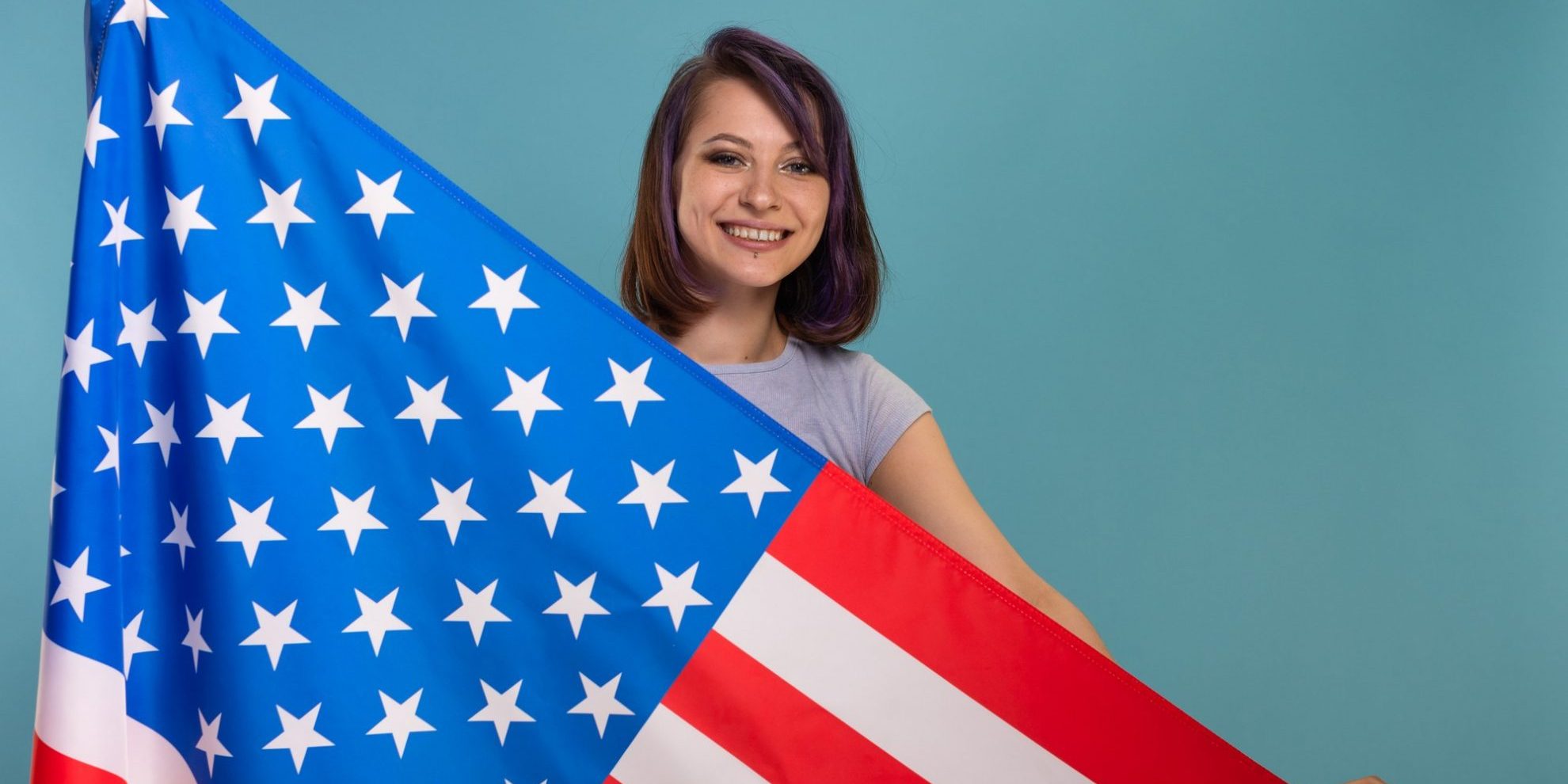 Foto de chica con bandera de Estados Unidos ilustra blog: "¿Cómo naturalizarse ciudadano de los Estados Unidos?"