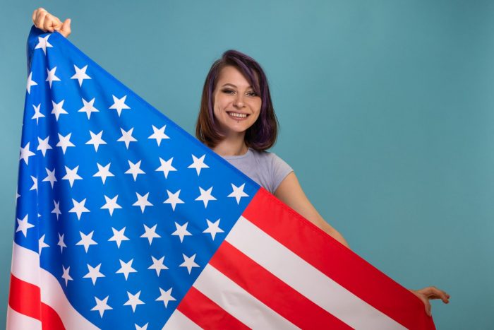 Foto de chica con bandera de Estados Unidos ilustra blog: "¿Cómo naturalizarse ciudadano de los Estados Unidos?"