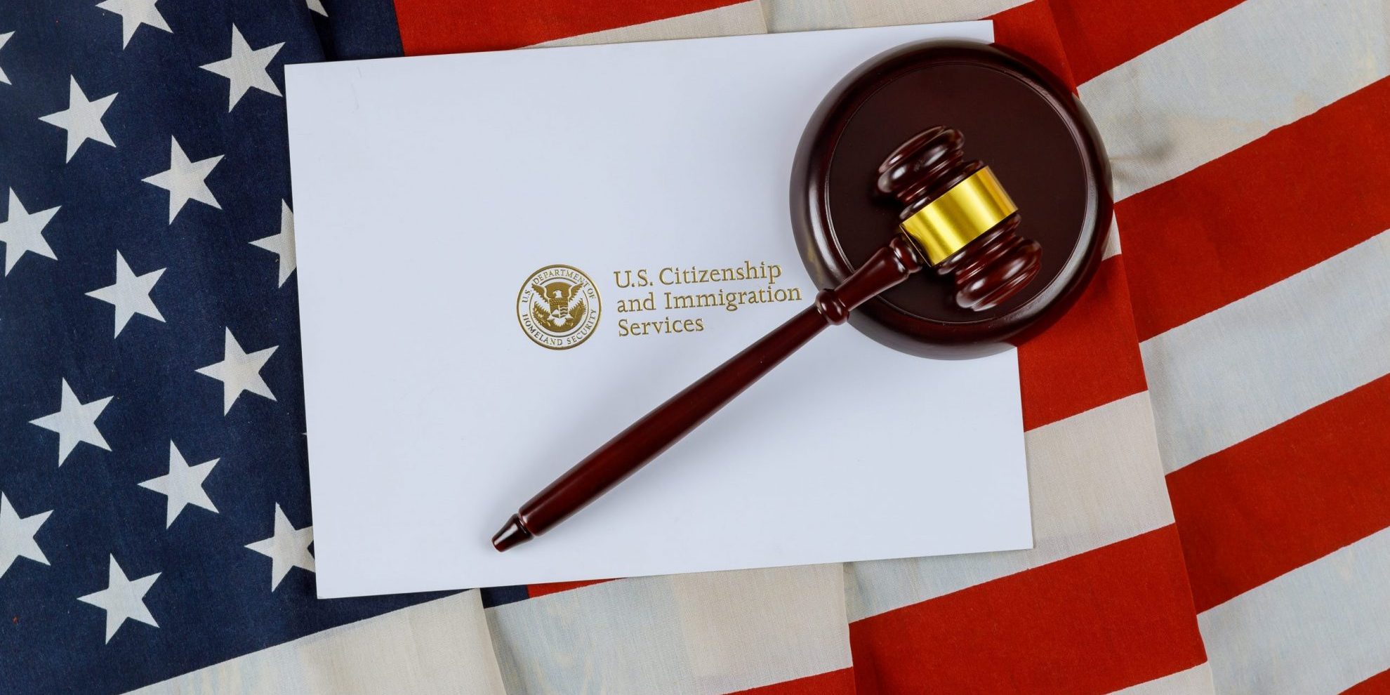 Imagen de bandera de estados unidos con documento que muestra el sello del USCIS ilustra blog: "Asilo en los Estados Unidos: 3 Cosas que necesitas saber"